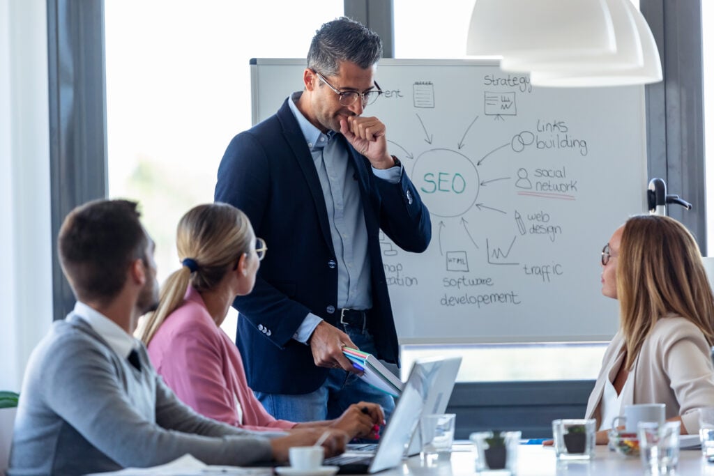 SEO expert explaining strategies to dental practice team using whiteboard diagram