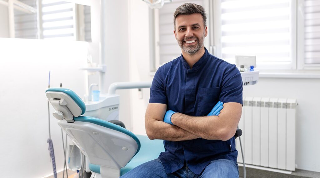 Professional dentist portrait in modern treatment room showing approachable team member